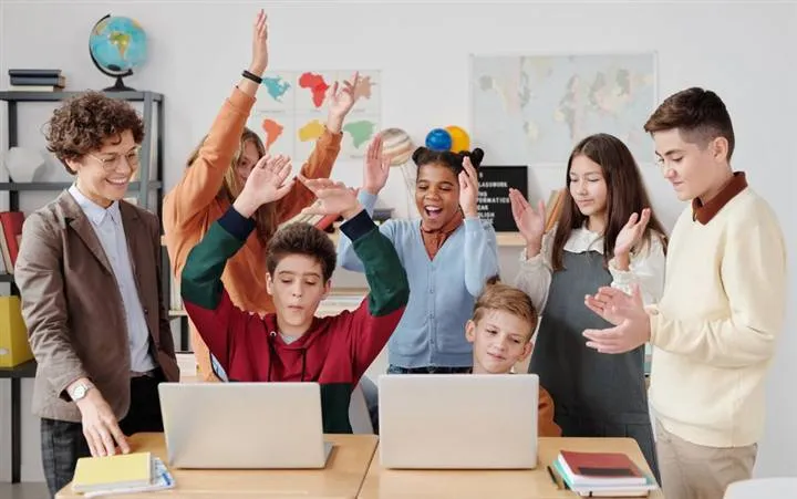 Kids and teens with hands up, energized during a Finance4u camp session